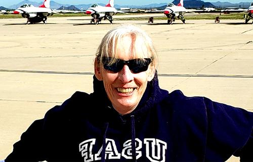 安妮特·珀金斯微笑地站在军事基地上，背后是喷气式飞机